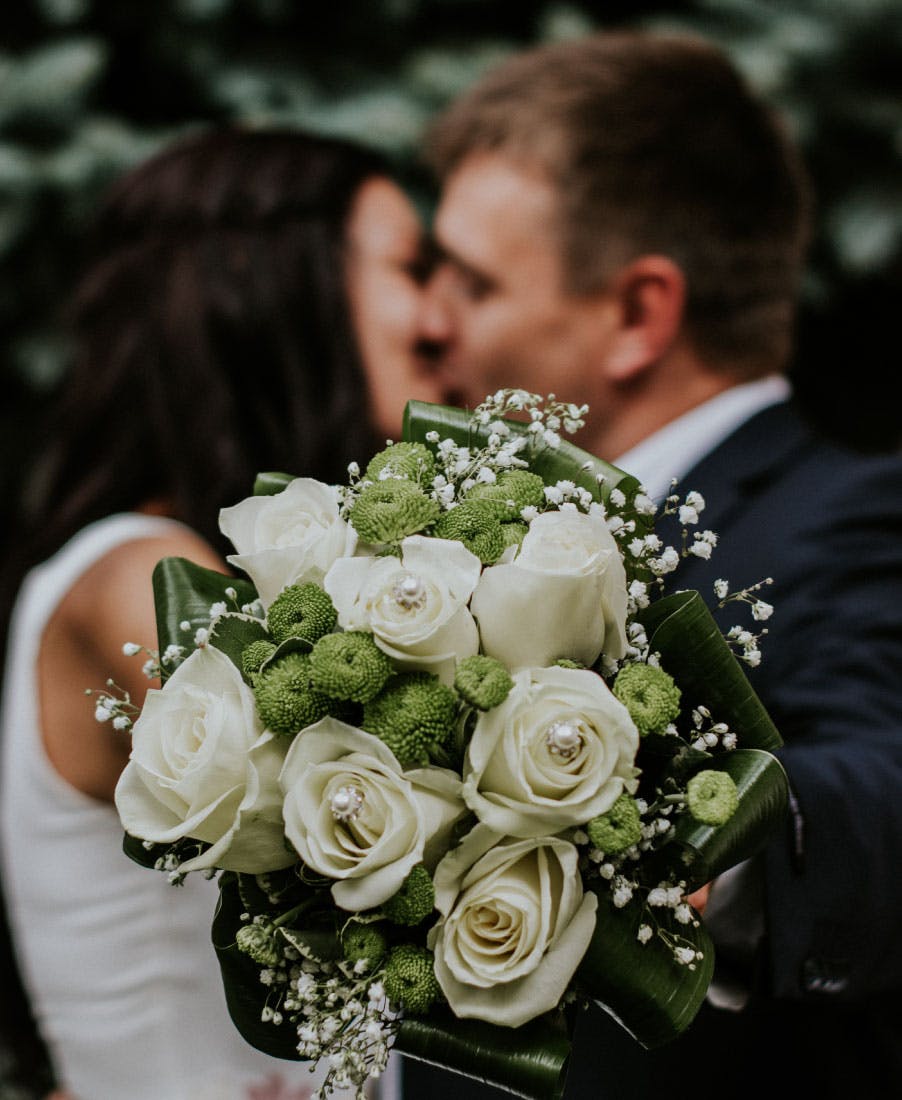 spouses-kissing-with-bouquet-of-flowers-in-hand